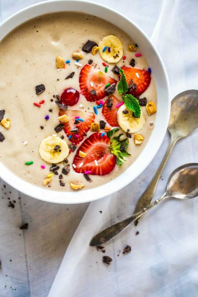 Colorful vegan smoothie bowl topped with tropical fruits like banana, pineapple, and mango, garnished with chia seeds and granola